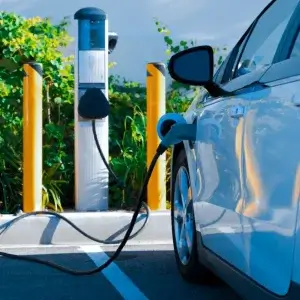 Vehículo eléctrico junto a estación de carga fija.